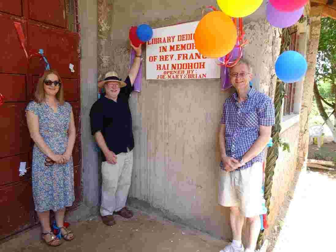Three visitors at the balloon-decorated plaque dedicating the library to the memory of Rev. Francis