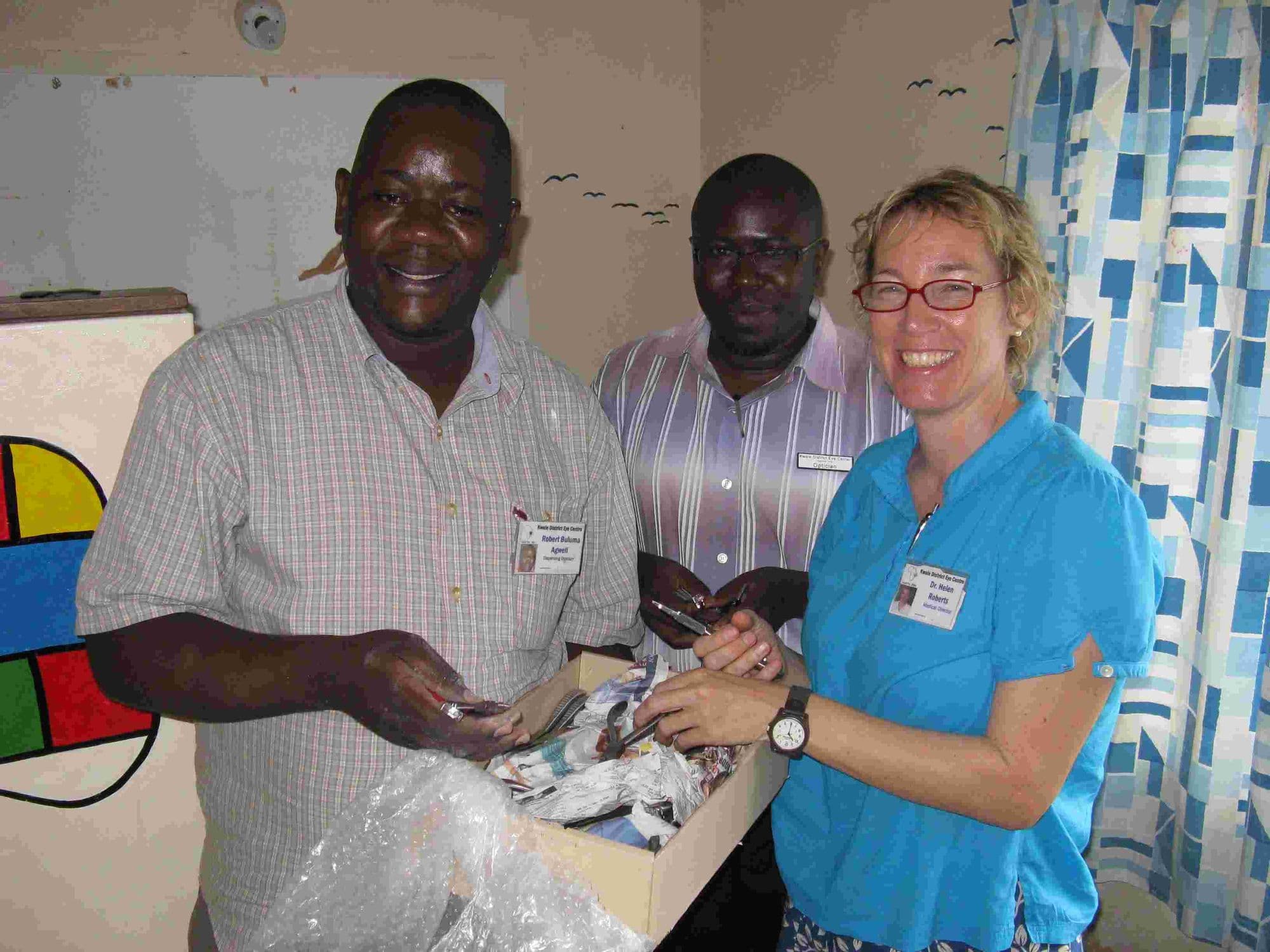 Eye clinic staff receiving a box of donated specialist eye equipment from a visitor