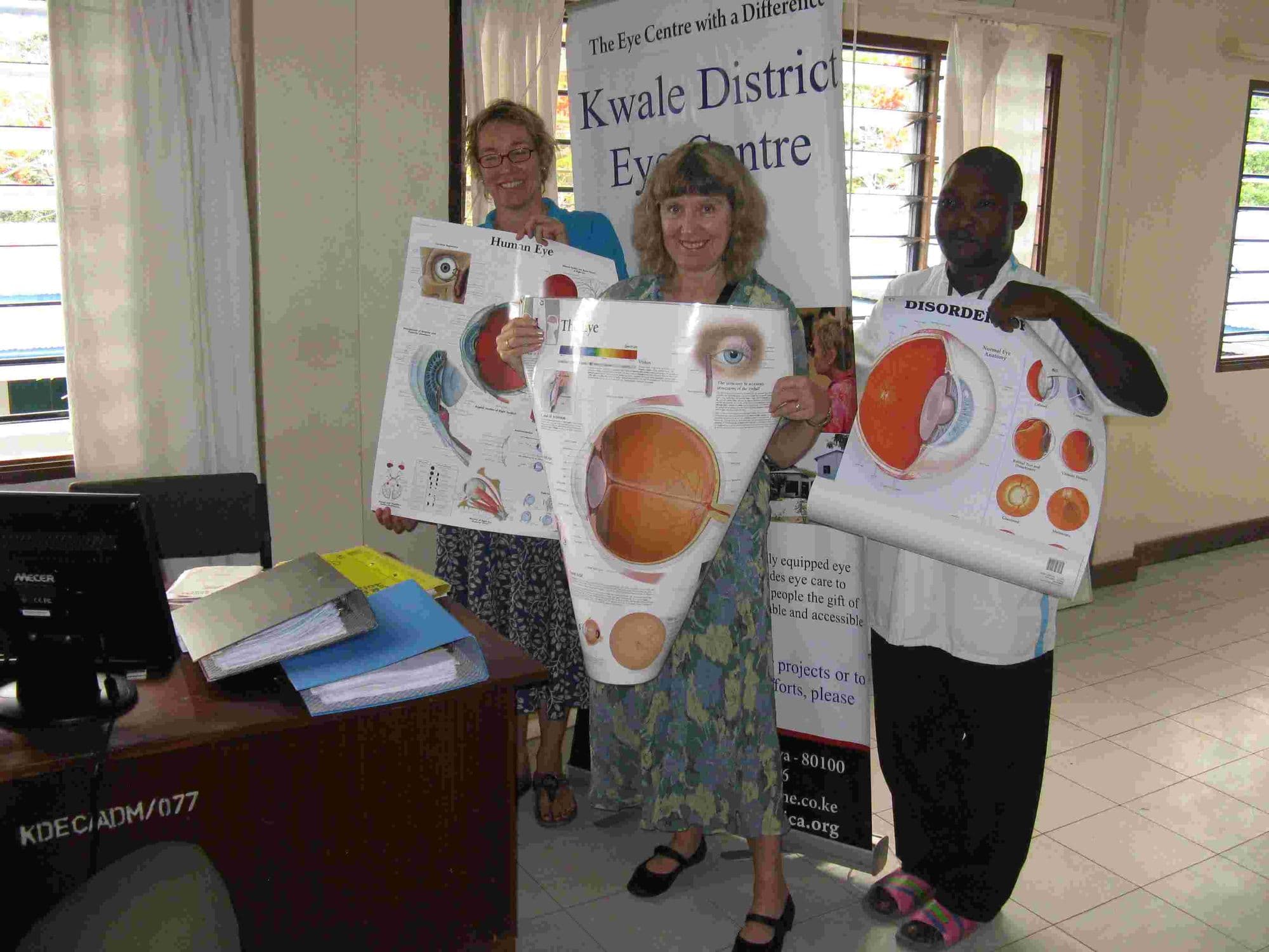 Visitors and staff holding up eye charts at the Kwale District Eye Centre