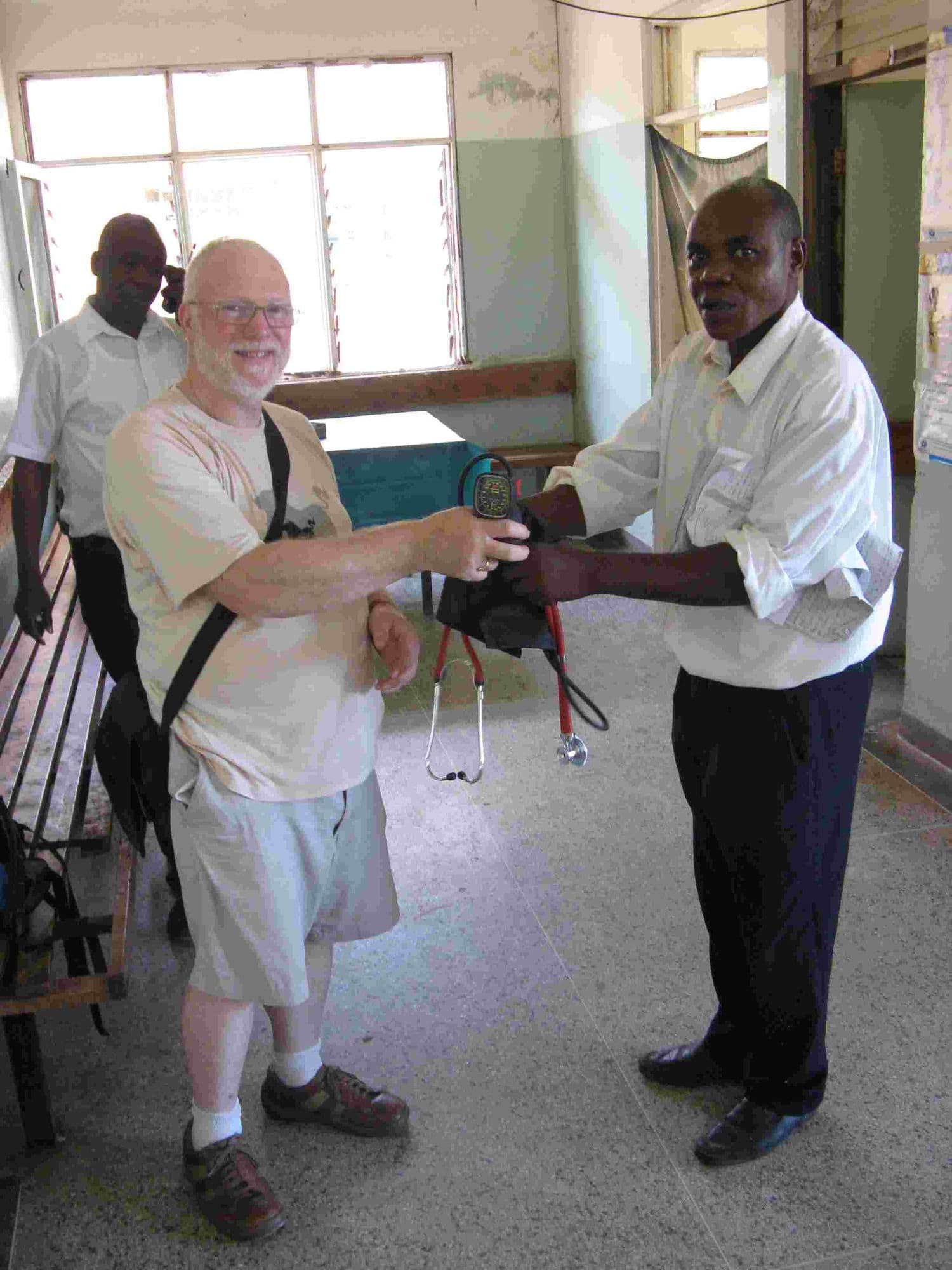 A visitor handing a stethoscope to a health worker