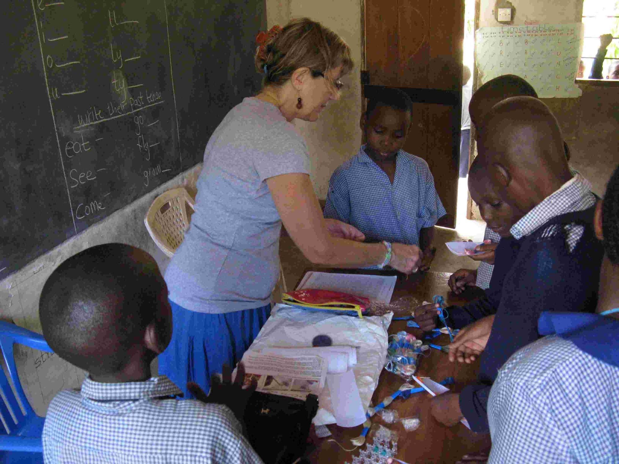 A visitor showing pupils how to do loom knitting at a table