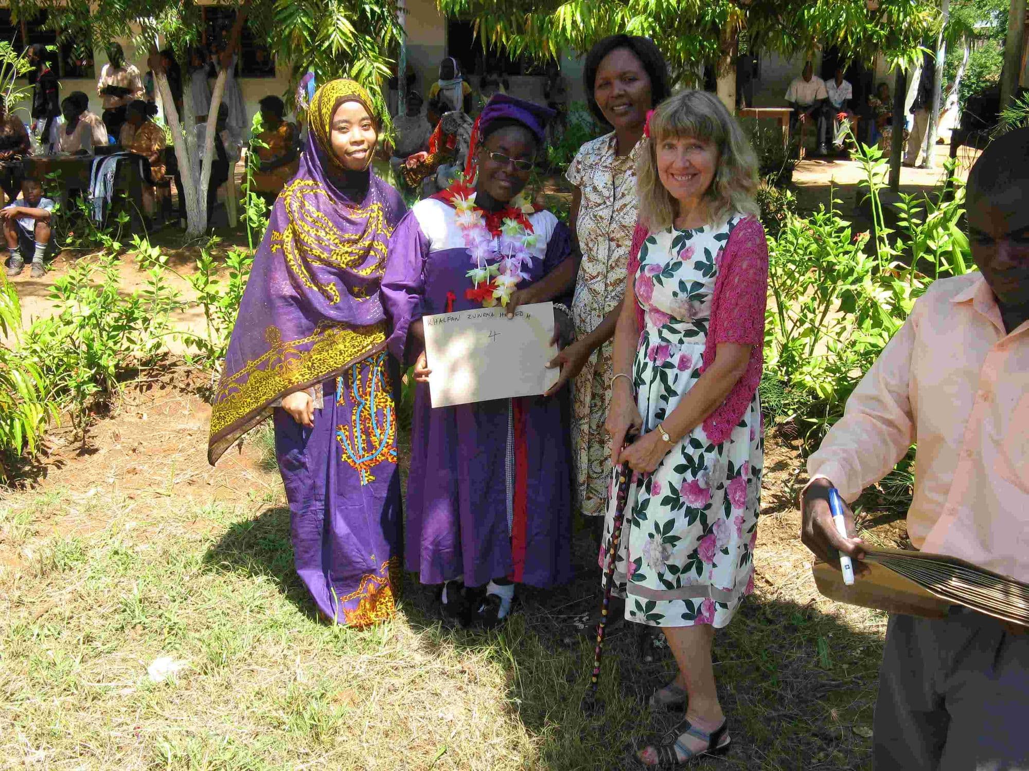 A graduate in a purple gown with her family and a visitor holding a certificate