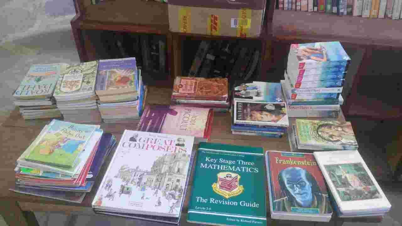 Donated children's books and revision guides spread on a table in front of DHL boxes