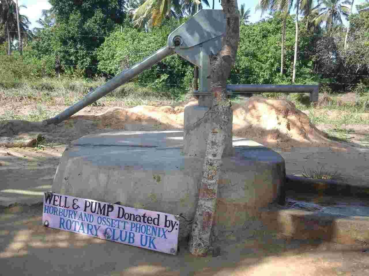 A hand pump on a concrete well with a sign saying it was donated by Horbury and Ossett Phoenix Rotary Club UK