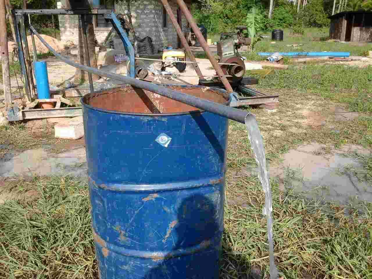 Water pouring from a new pipe into a blue oil drum at the orphanage