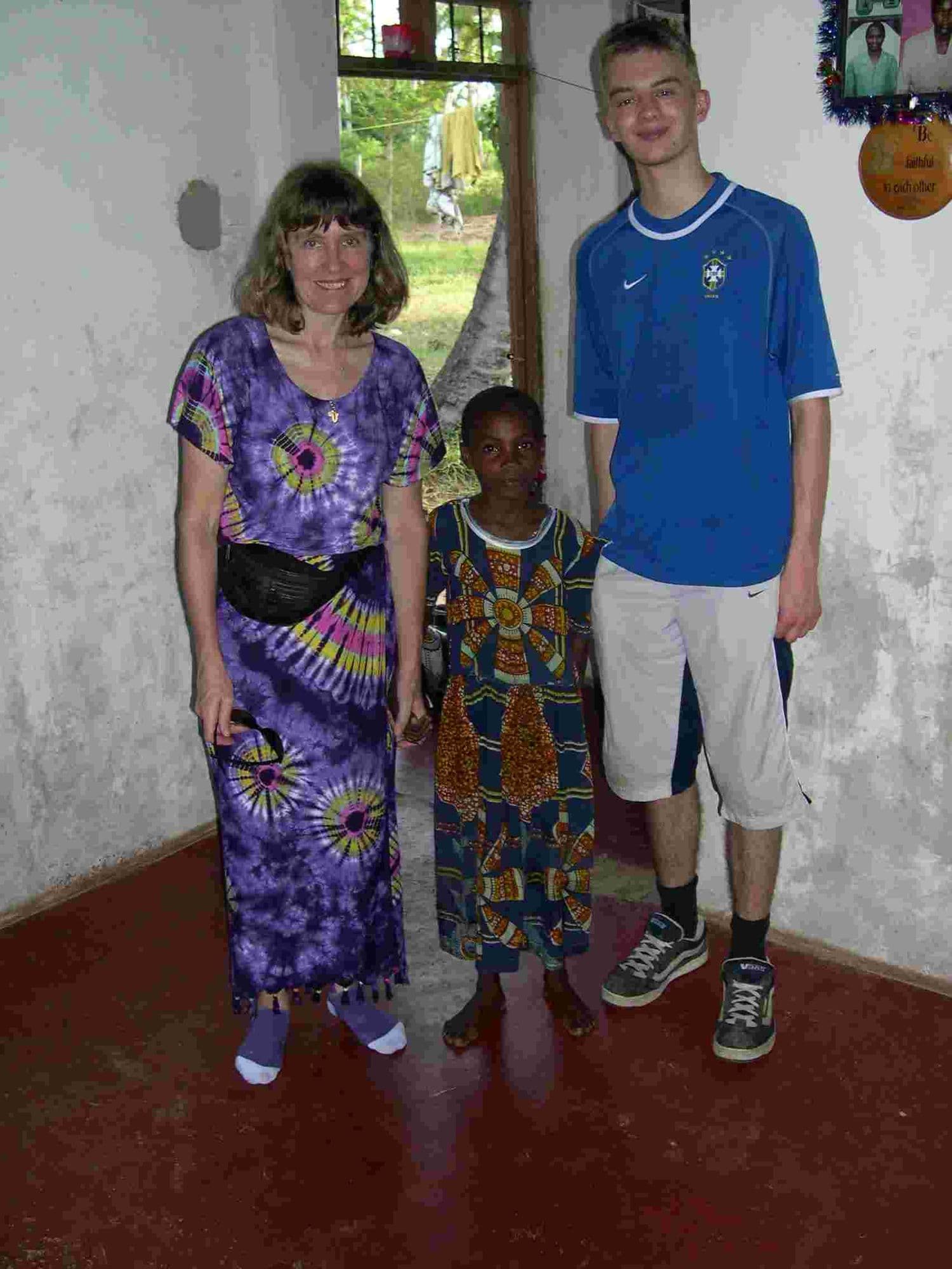 A woman, a small girl and a teenage boy standing together in a room