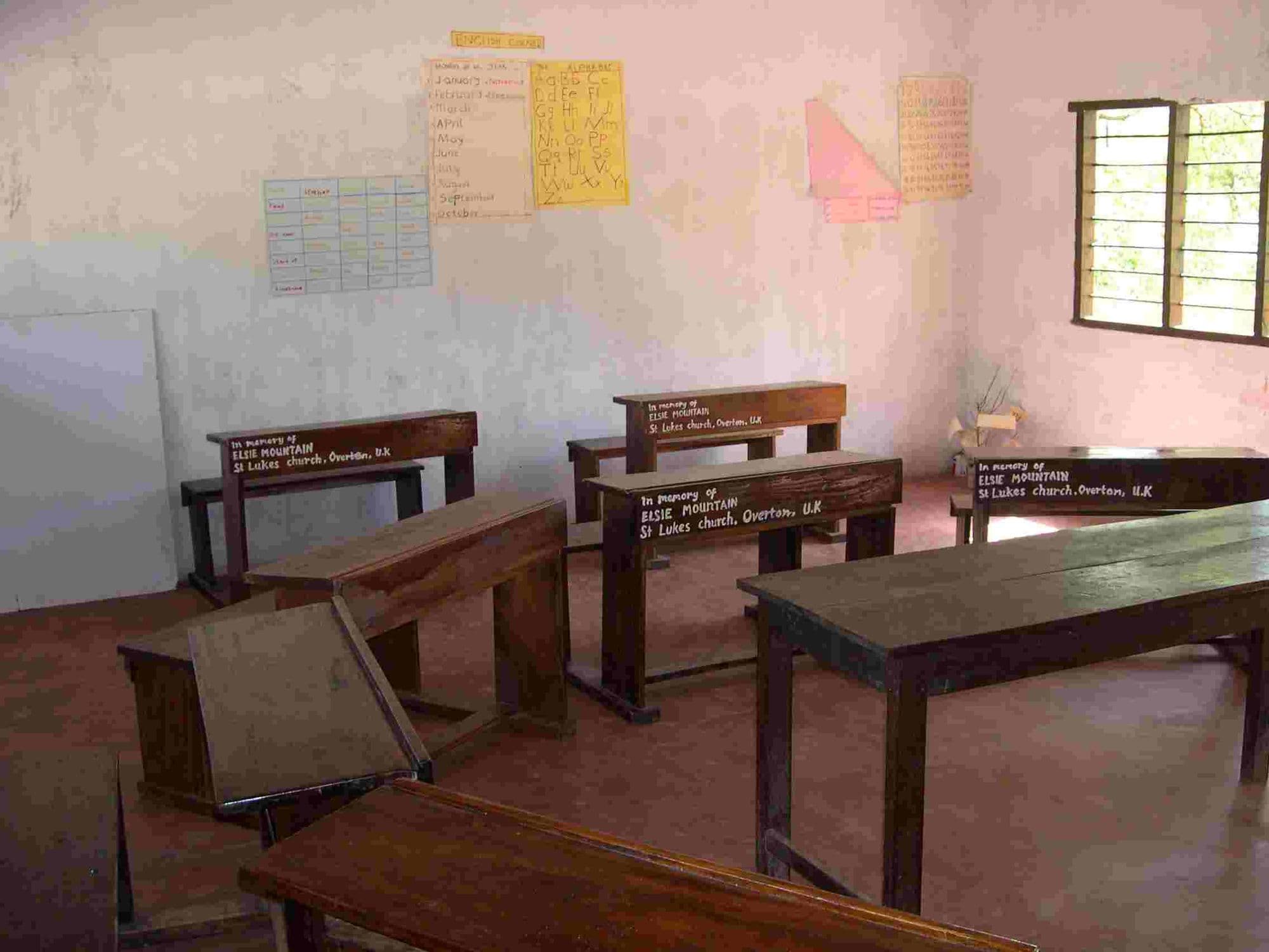 Wooden double desks with sponsors' name plates in an empty classroom