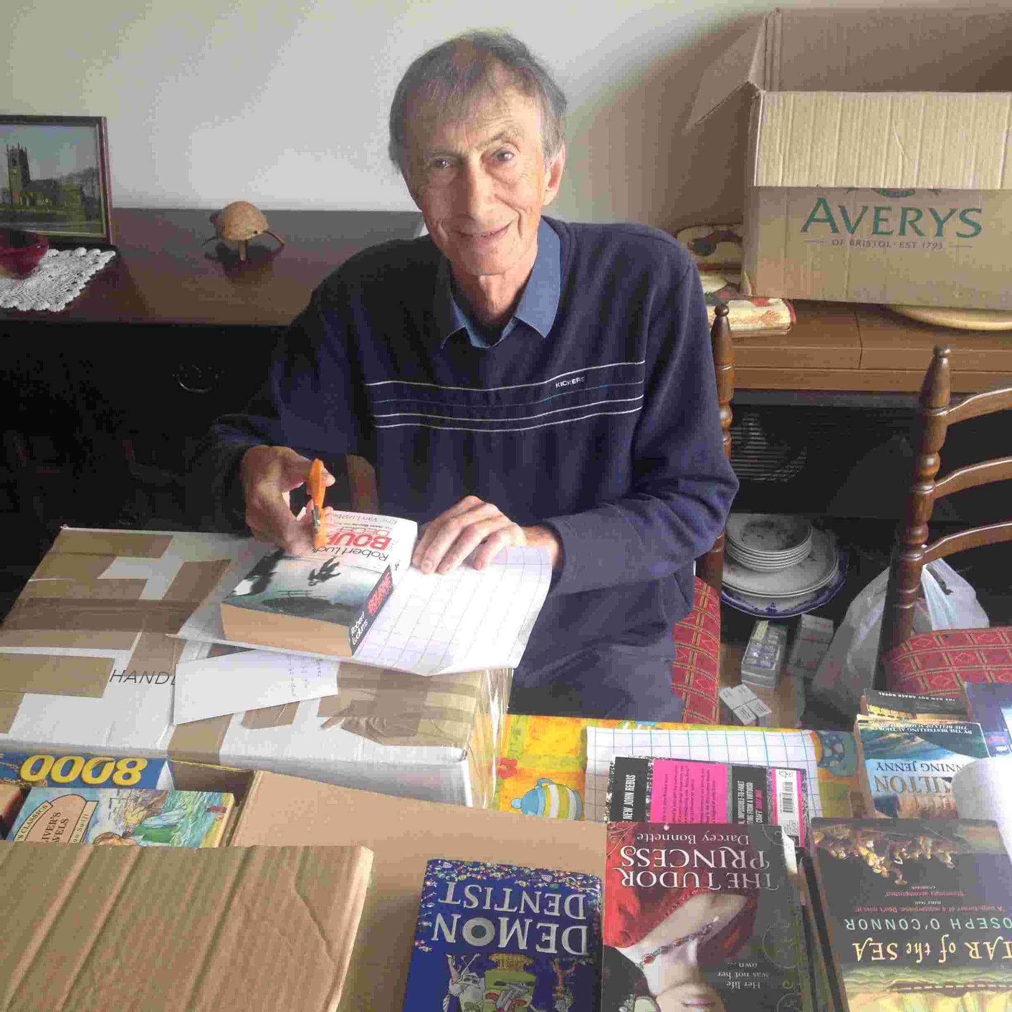 A visitor at home in the UK covering a pile of donated children's books