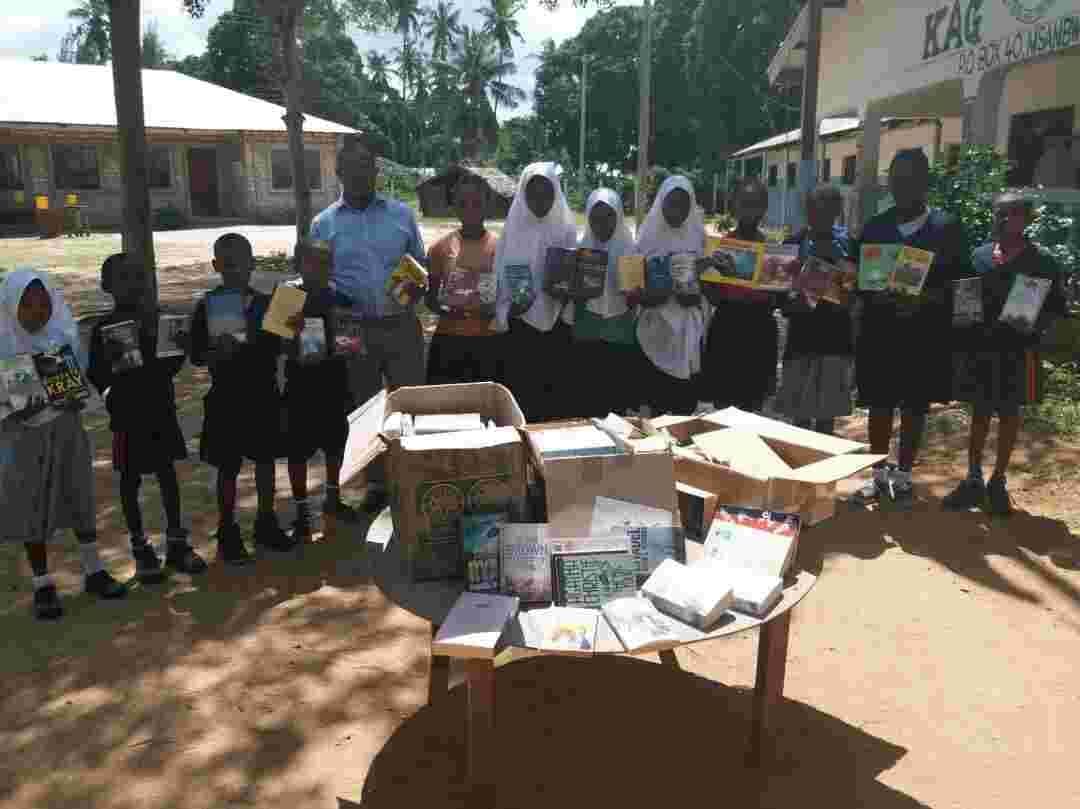 Pupils holding up new books around a table of opened book boxes