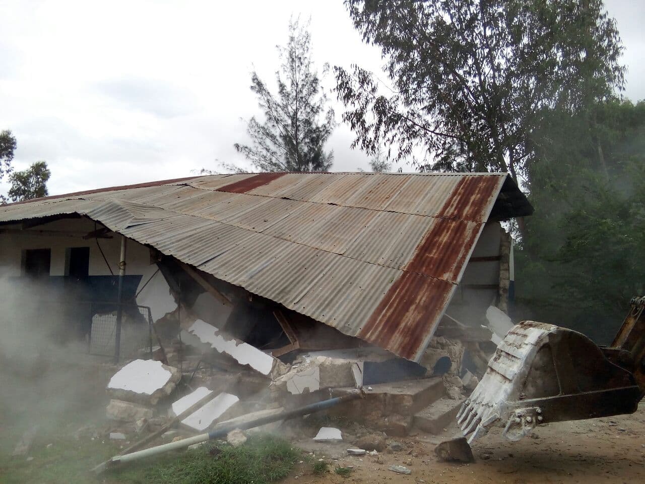 The flattened iron roof of the nursery classroom lying on the rubble