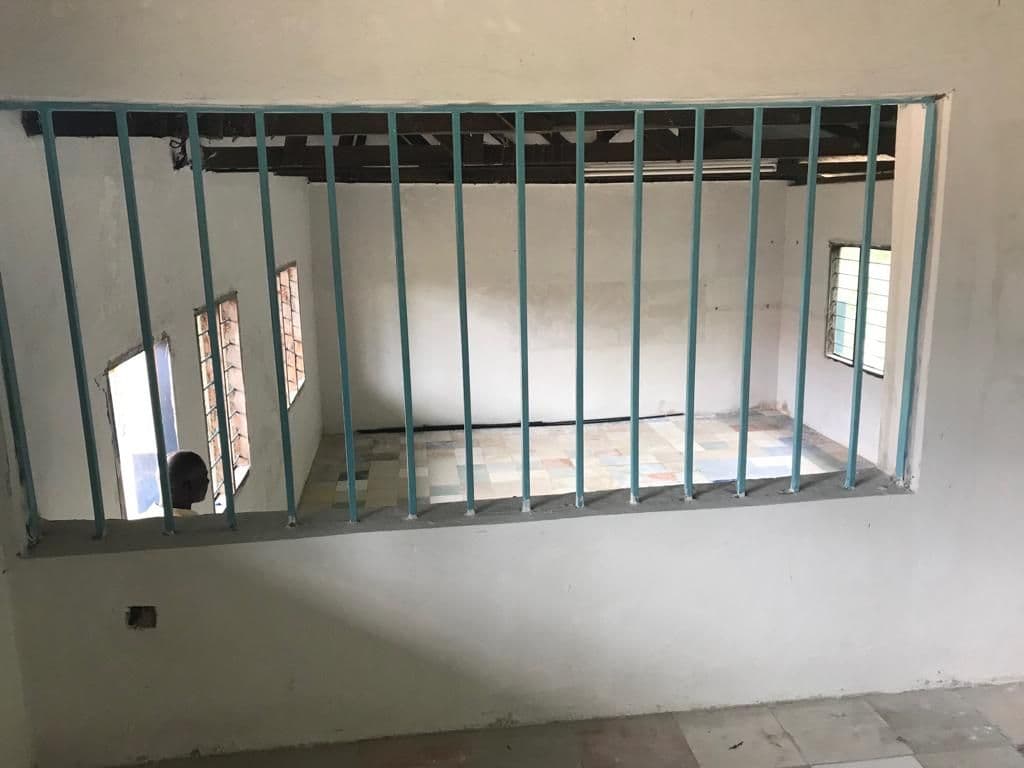 Barred window opening in the wall of the former classroom being converted