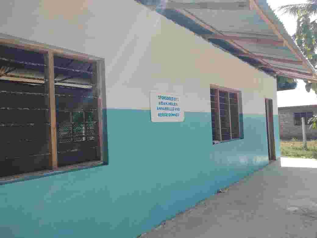 Outside wall of a new blue and white classroom with a plaque by the door