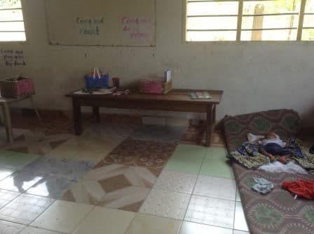 A nursery classroom set up with a play table and a sleeping mat on the tiled floor