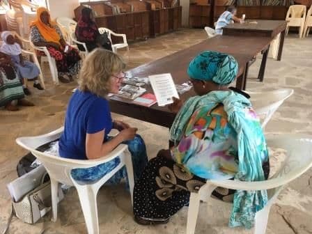 A visitor teaching a woman to make sanitary wear at a library table