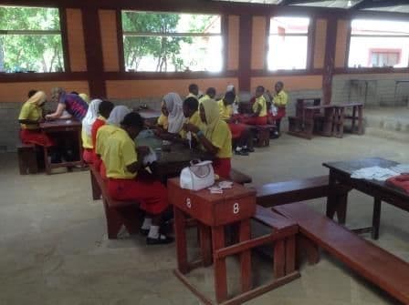 Schoolgirls cutting out fabric at desks during the sanitary wear session