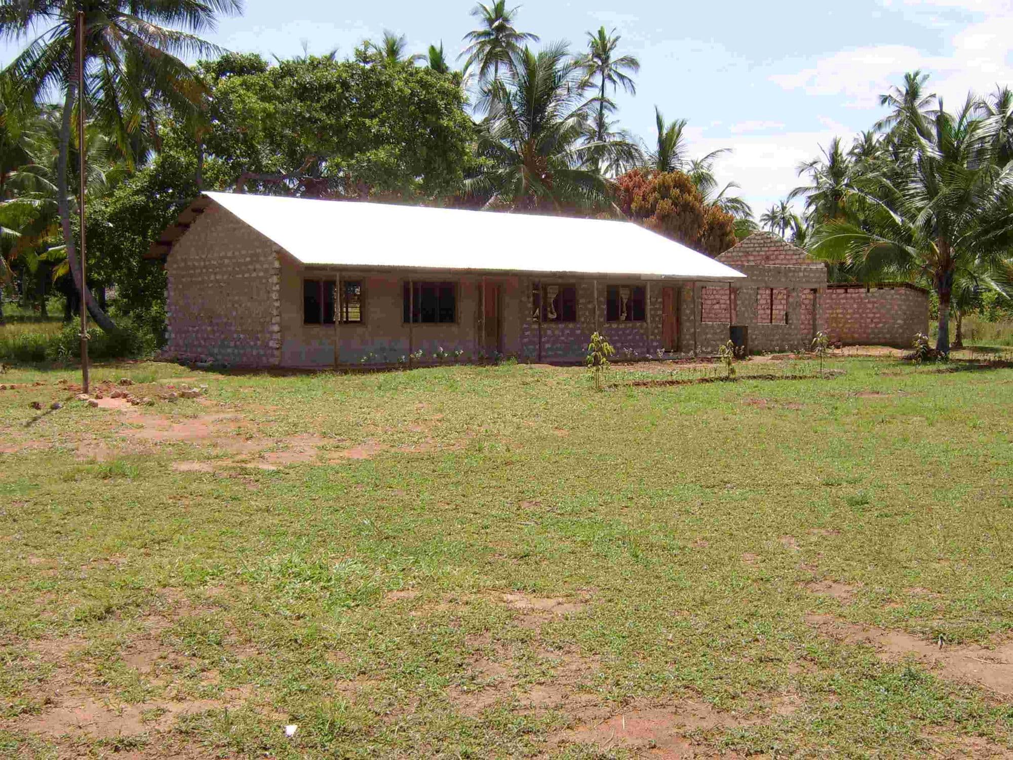 A newly built classroom block with an iron roof standing on a grassy field