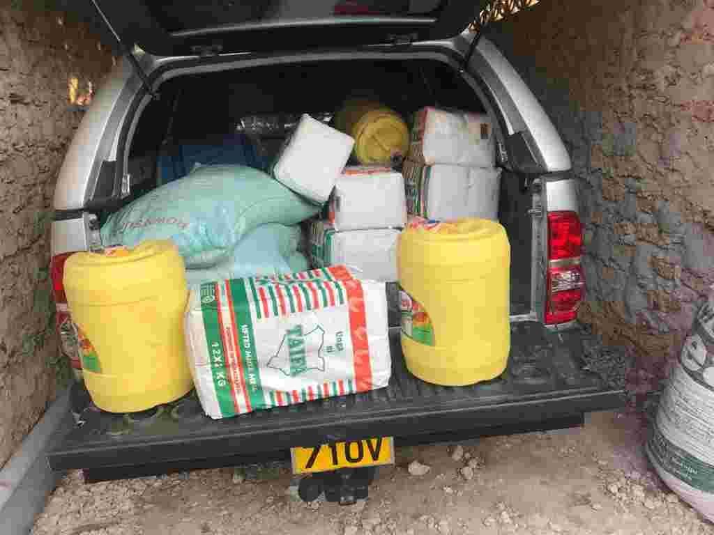 The back of a pickup loaded with sacks of flour and jerrycans of cooking oil for families