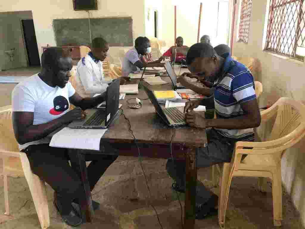 Teachers working on laptops at a table in a classroom