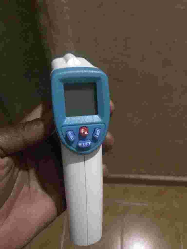 A hand holding an infrared thermometer