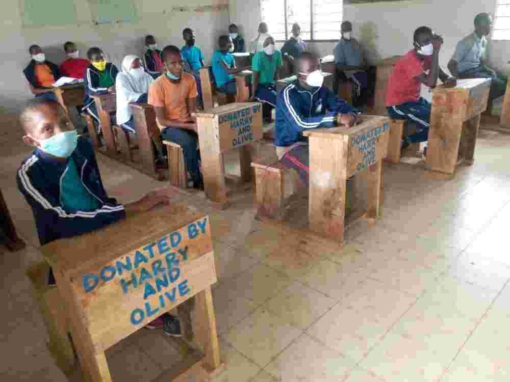 Masked pupils sitting at single desks spaced apart in a classroom