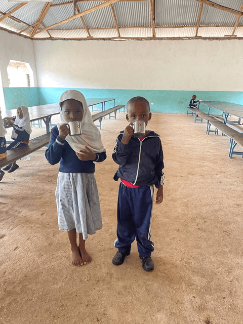 Two young pupils drinking porridge in the dining room