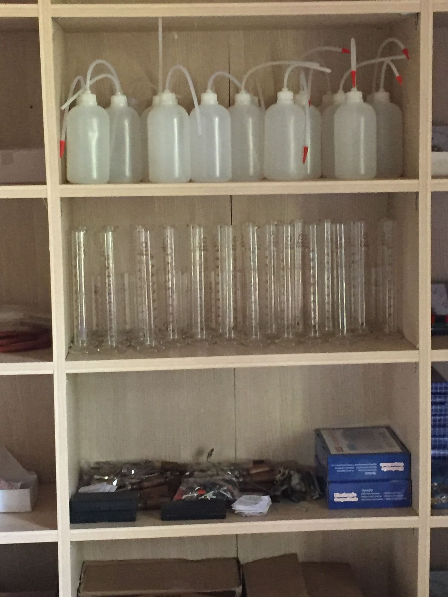 Lab shelves stocked with wash bottles, measuring cylinders and equipment