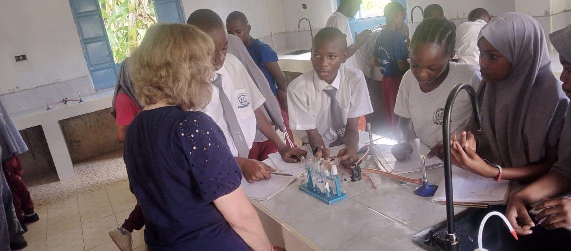 A visitor watching Junior High pupils carry out an experiment at a lab bench