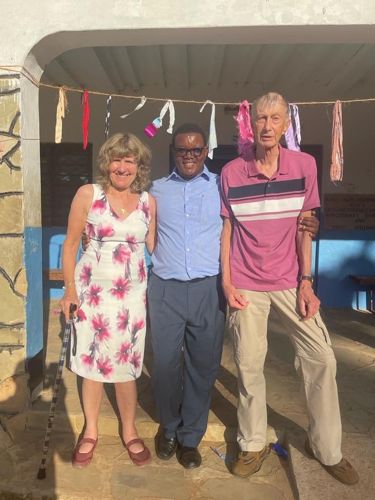 Two visitors standing with a teacher at the graduation ceremony