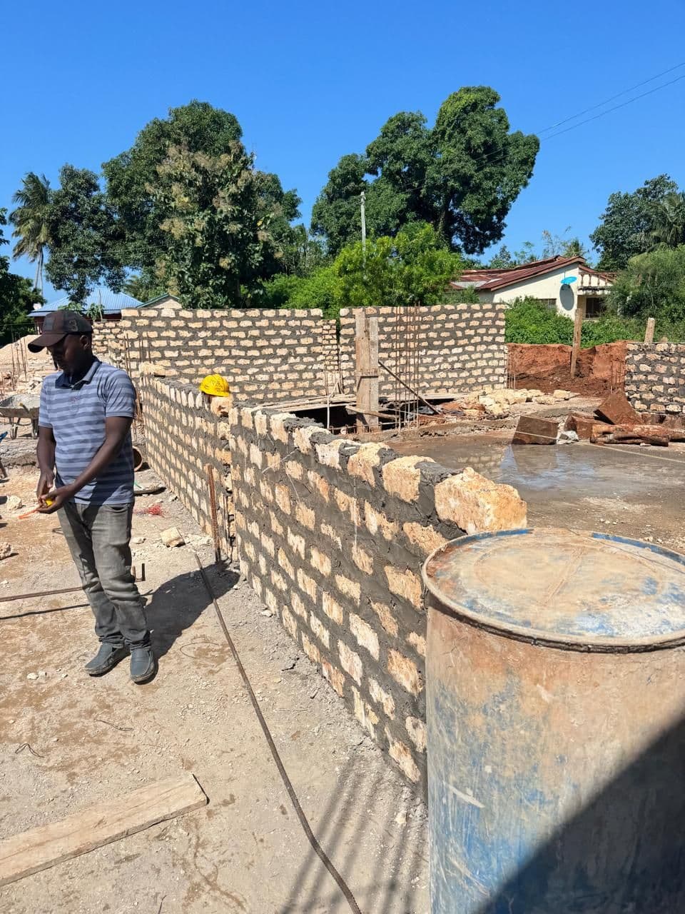 A builder beside the block walls rising for the new classrooms