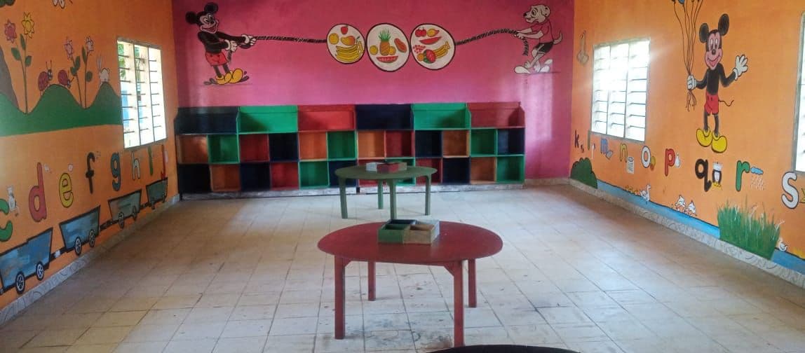 The painted baby classroom with a red table and toy shelves