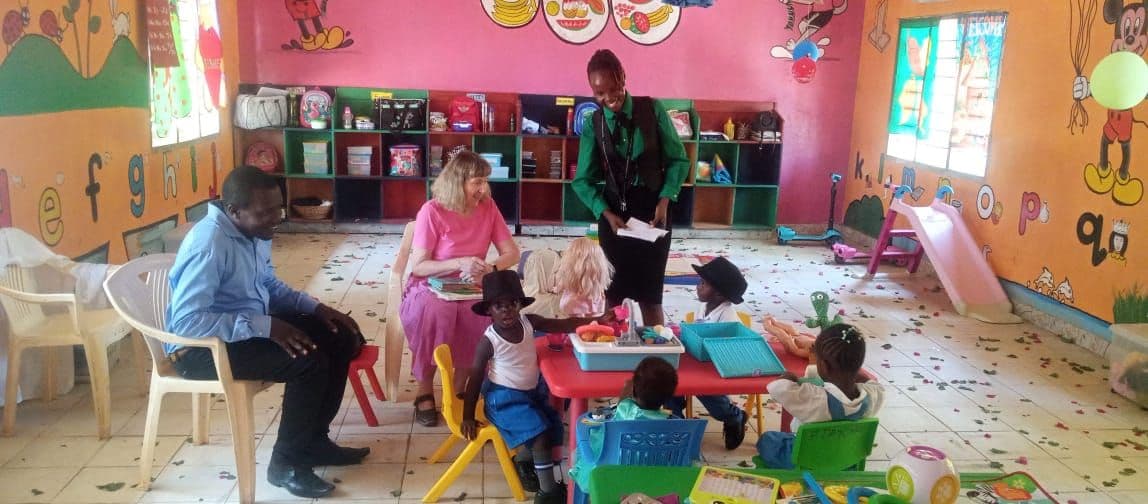 Visitors and staff sitting with babies playing with toys at small tables