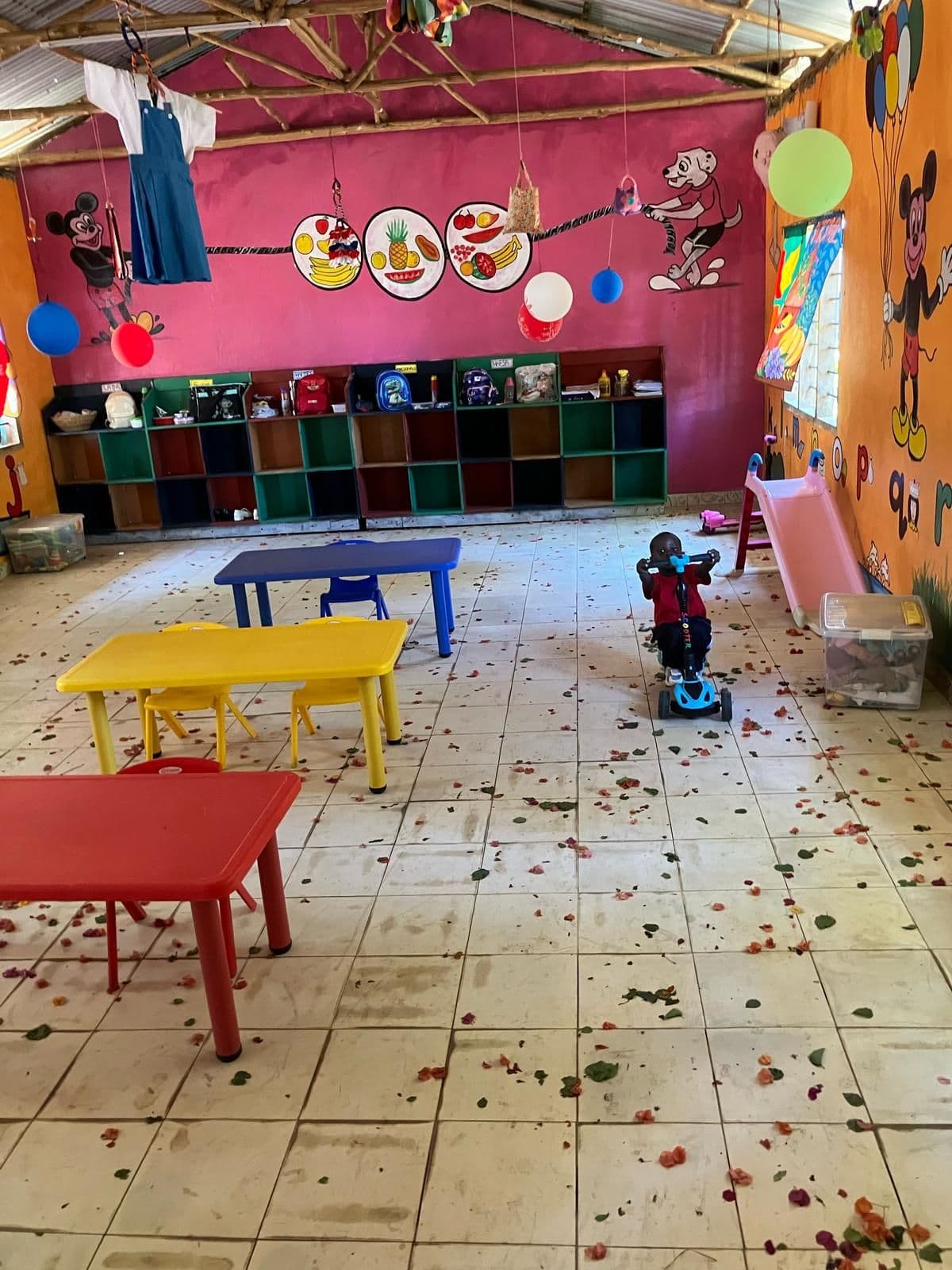 A child riding a toy car across the baby classroom