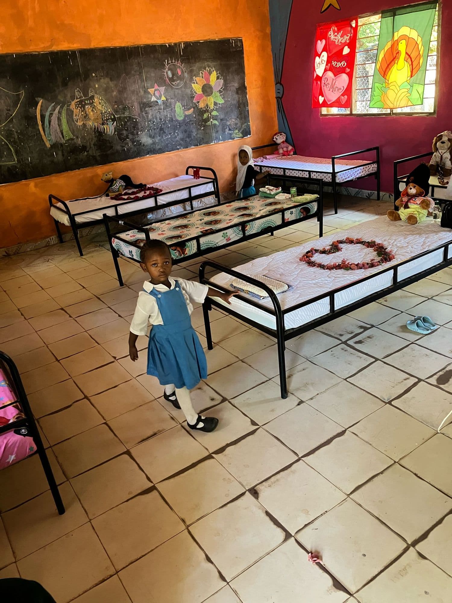 A young pupil standing between rows of small beds in the baby class rest room
