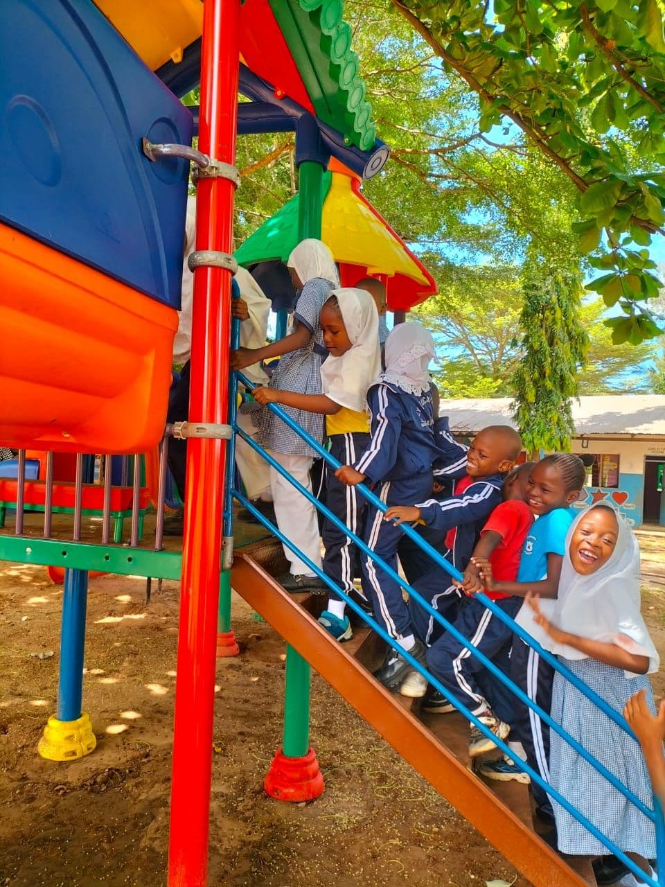 Young pupils climbing the steps of a colourful outdoor slide