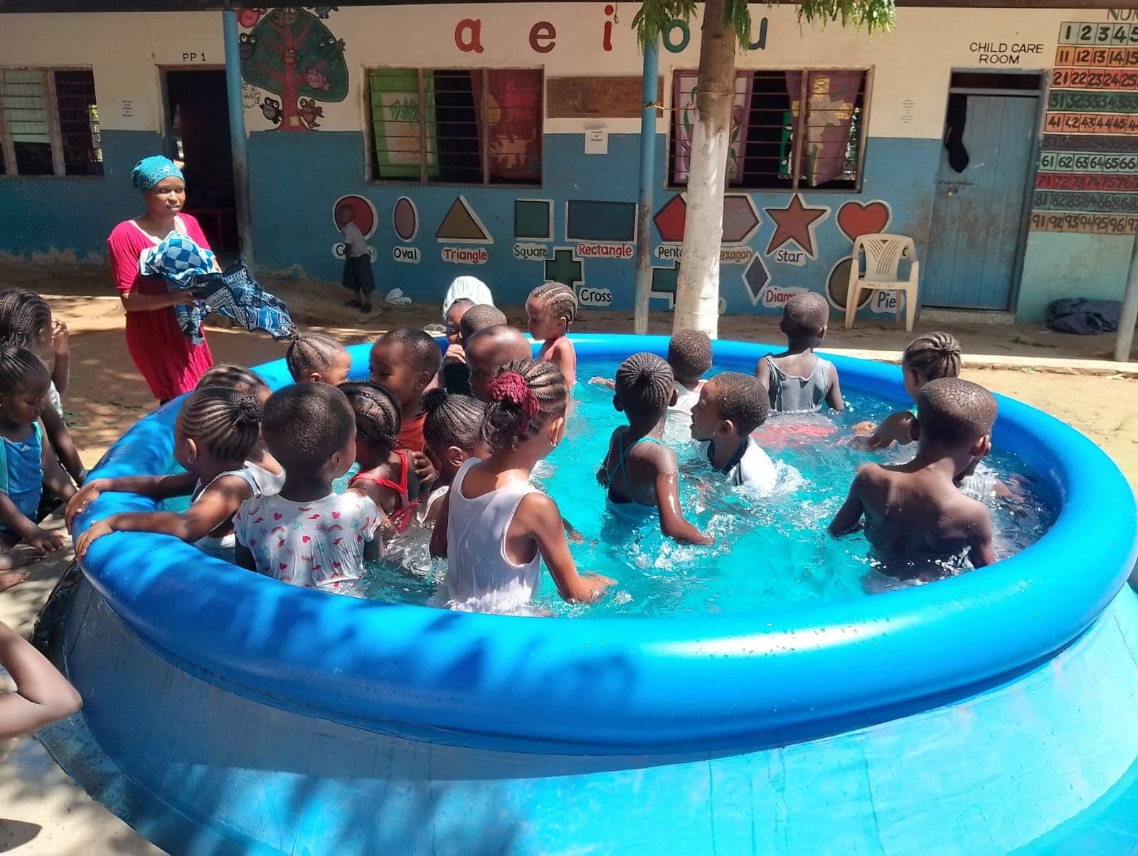 Young children splashing in a blue paddling pool in the school yard