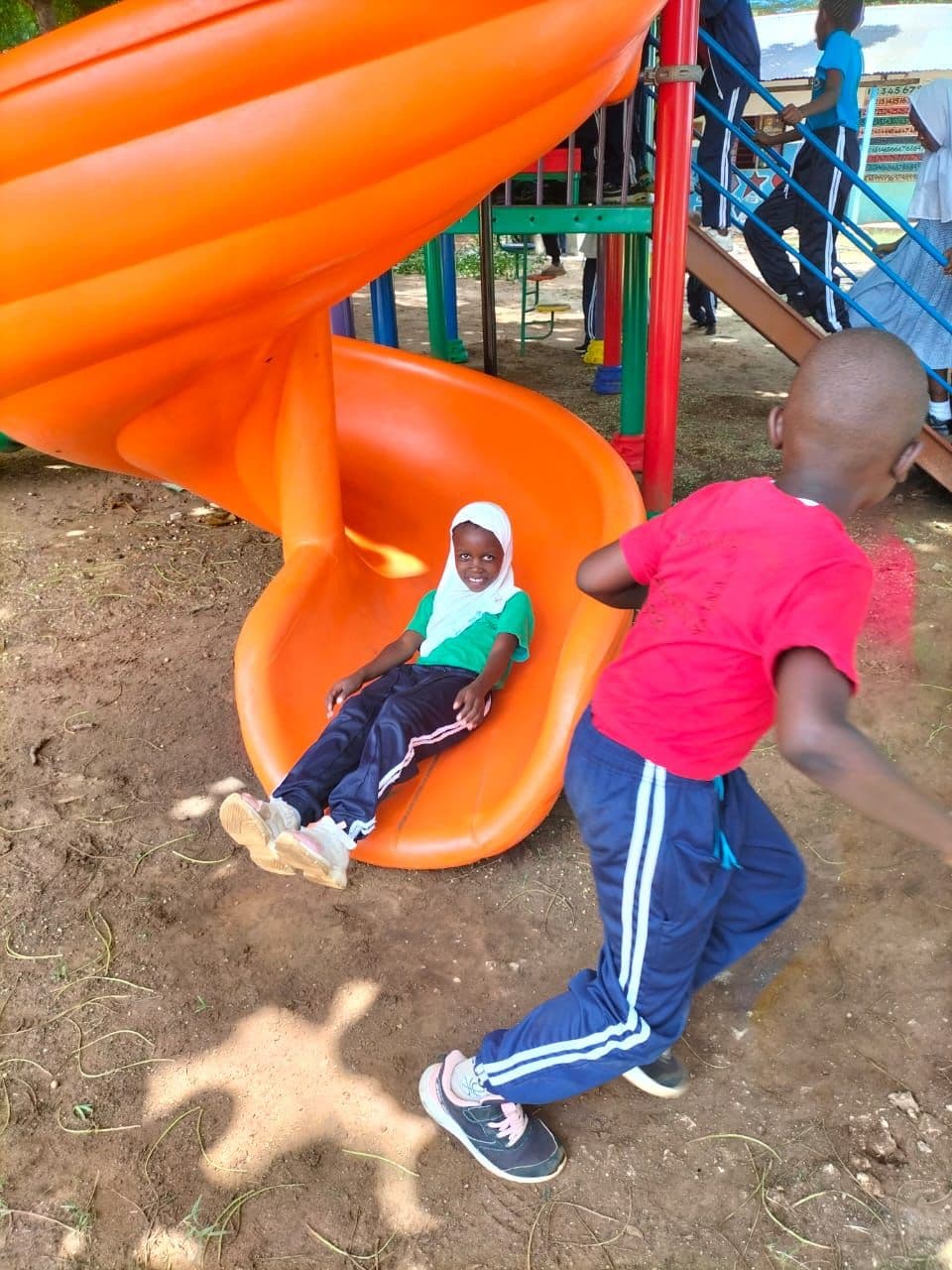 A pupil coming down an orange spiral slide