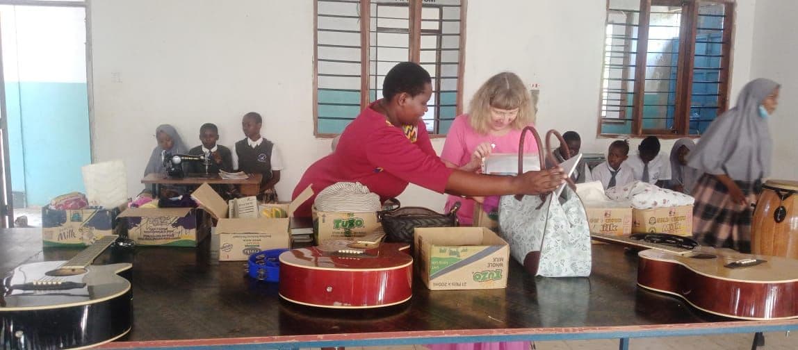 Visitors unpacking guitars and boxes of equipment on classroom tables