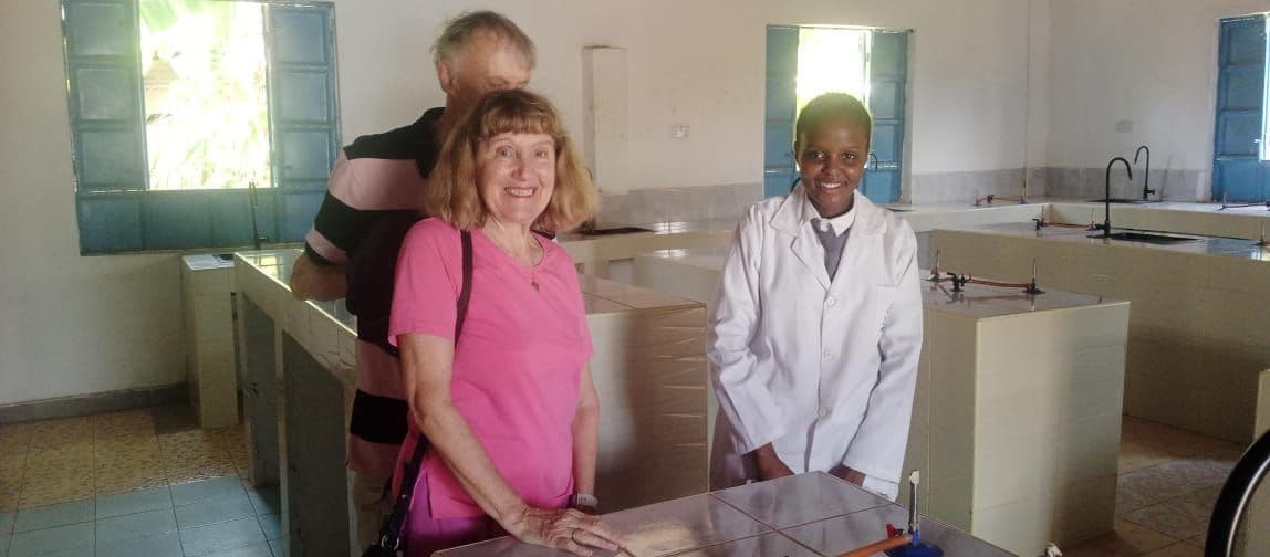 A visitor standing with a teacher in a white lab coat in the science lab