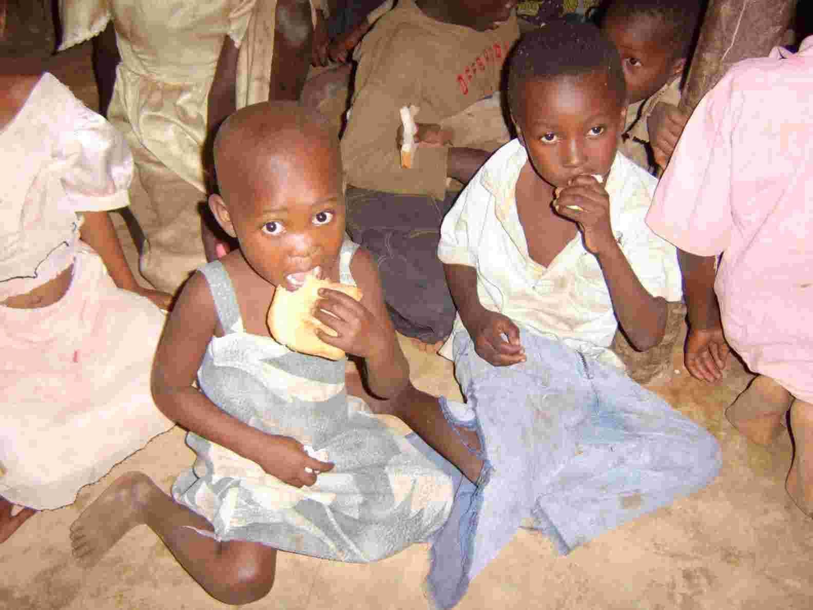 Young children sitting on the floor eating bread