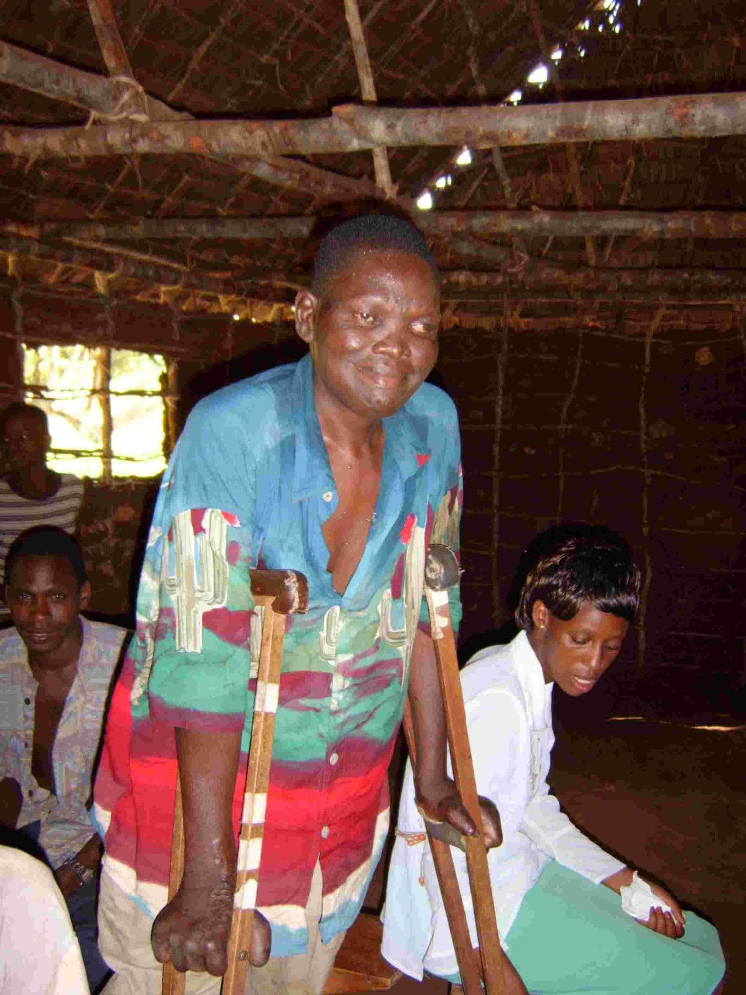 A woman on crutches standing inside a thatched building
