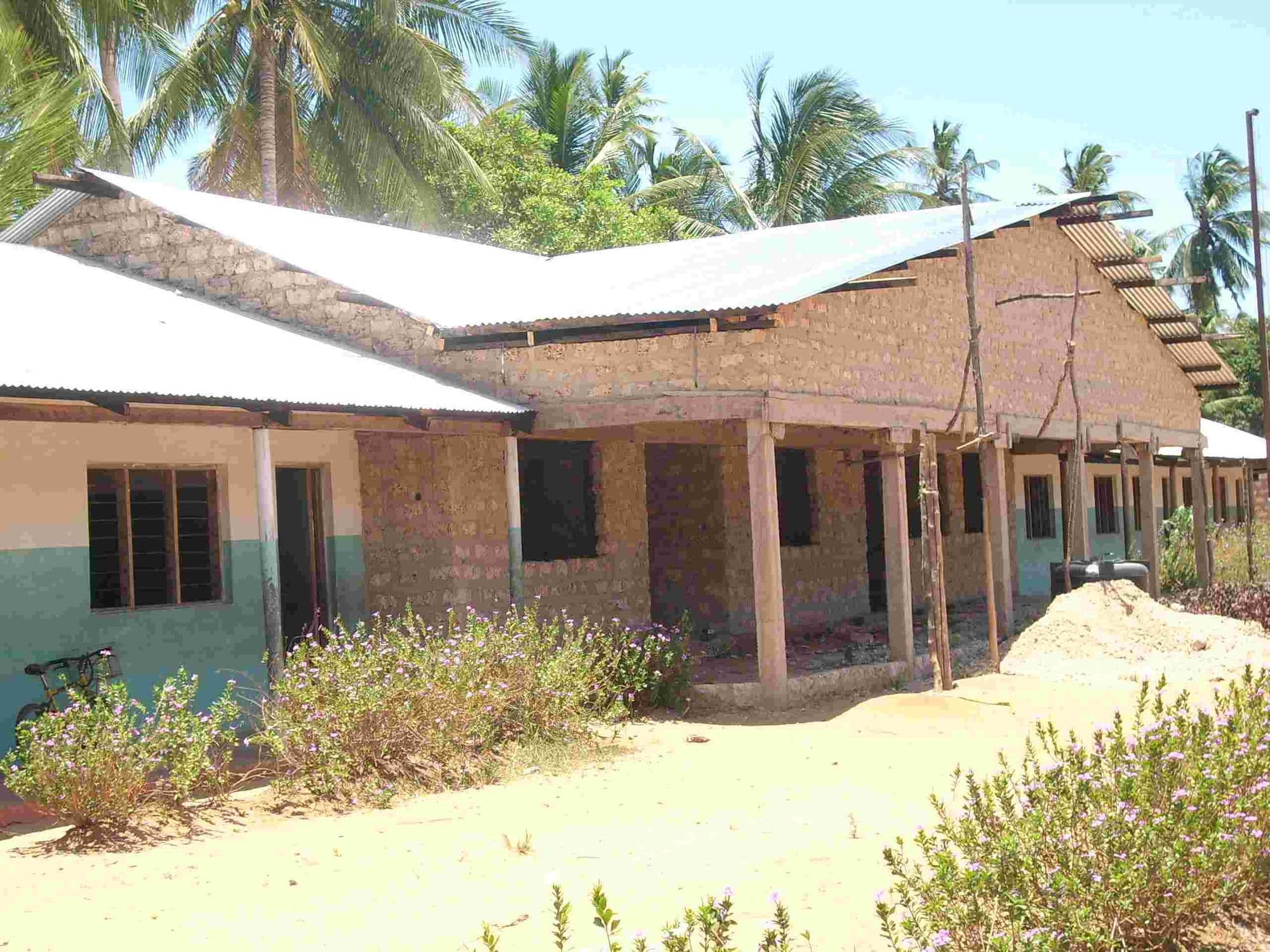 The administration block under construction with a long verandah and iron roof