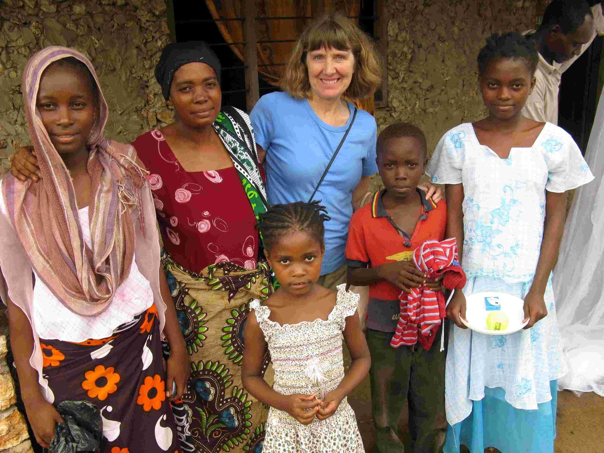 A visitor with a mother and her children outside their home