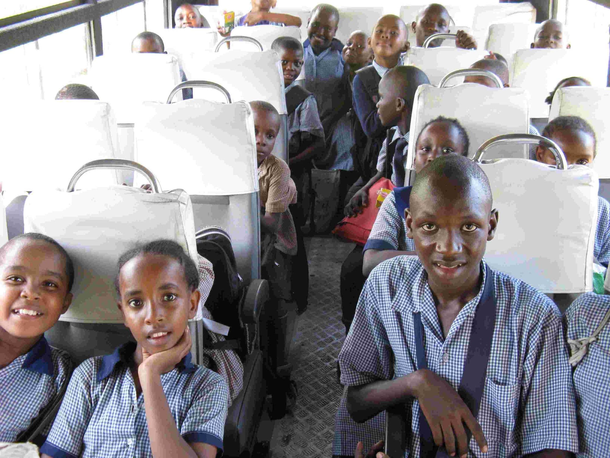 Smiling pupils in uniform seated inside the school bus