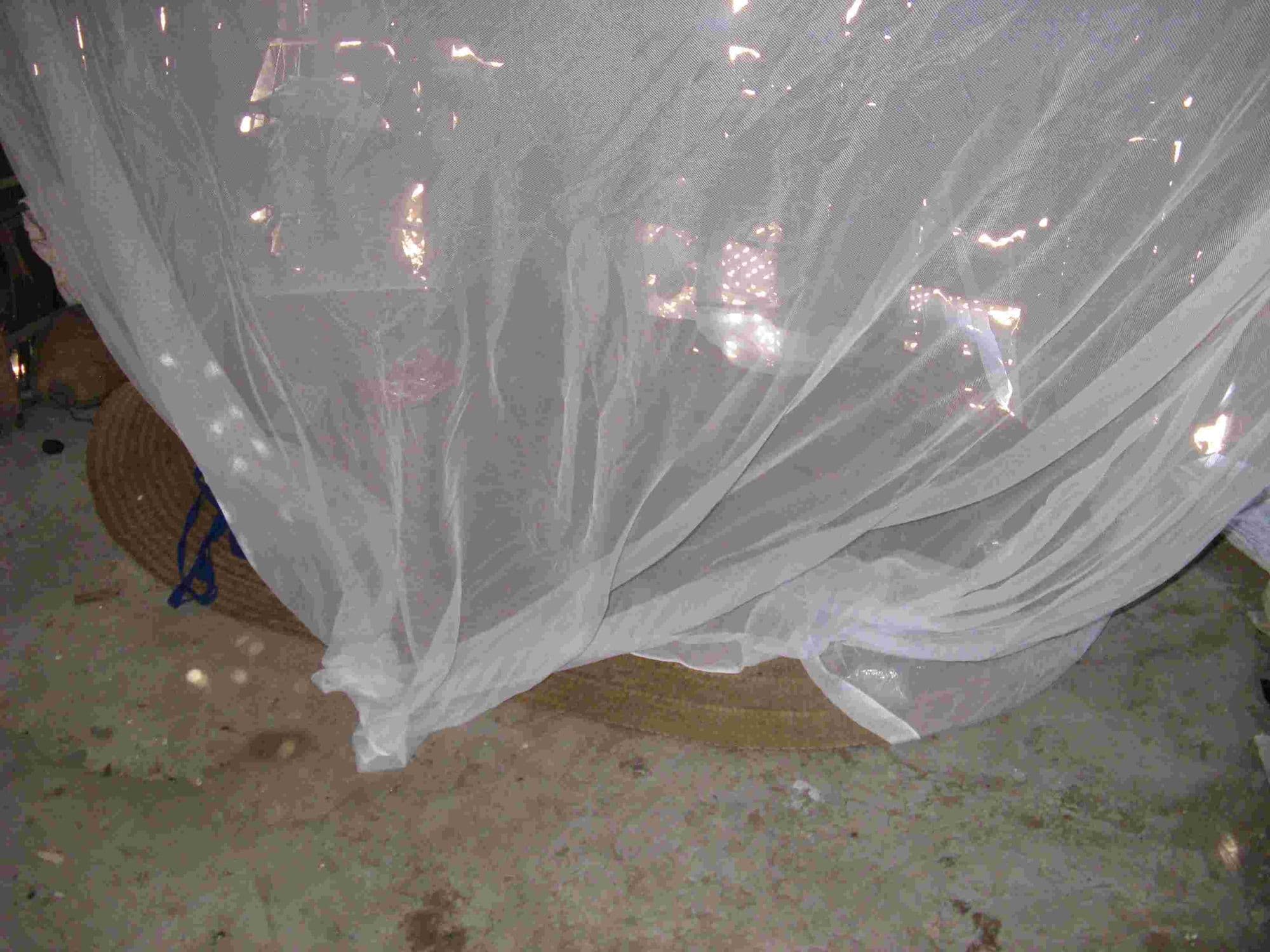 A mosquito net hung over a mat on the floor where there is no bed