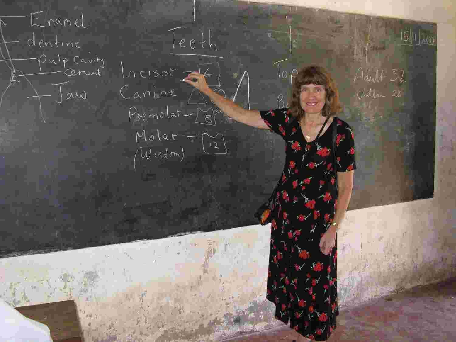 A teacher pointing to a blackboard lesson on the types of teeth