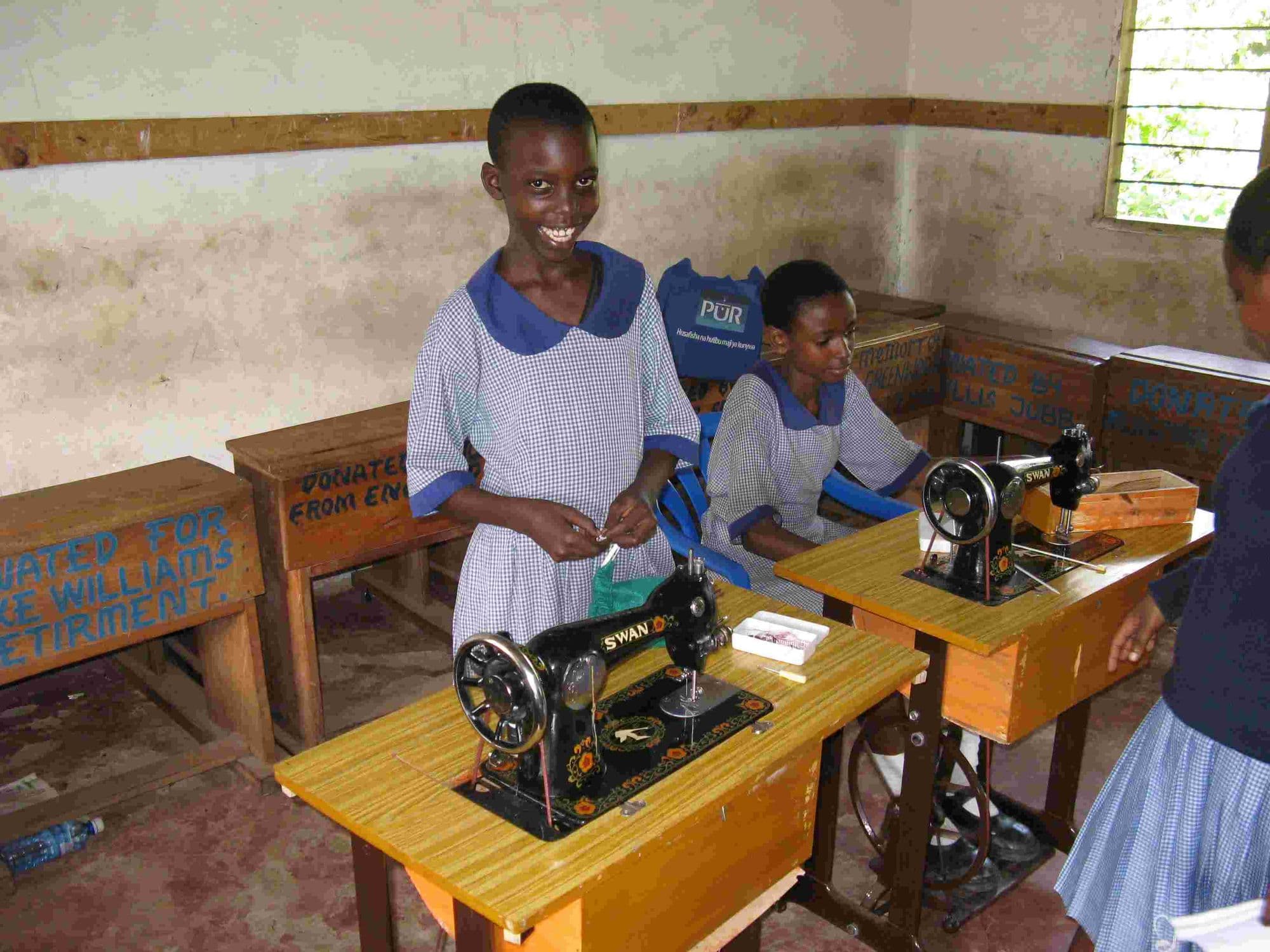 Pupils at a pair of treadle sewing machines in a classroom