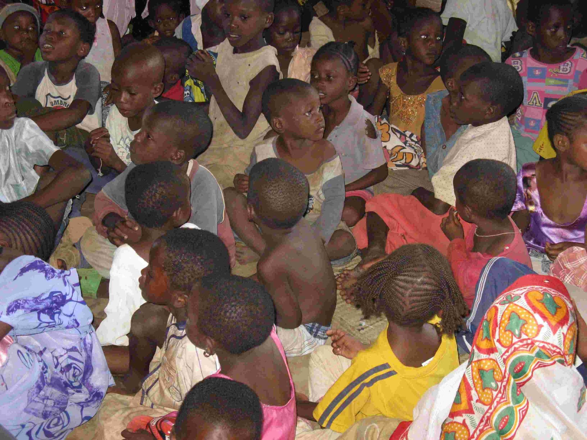 A crowd of young children sitting closely together on a floor