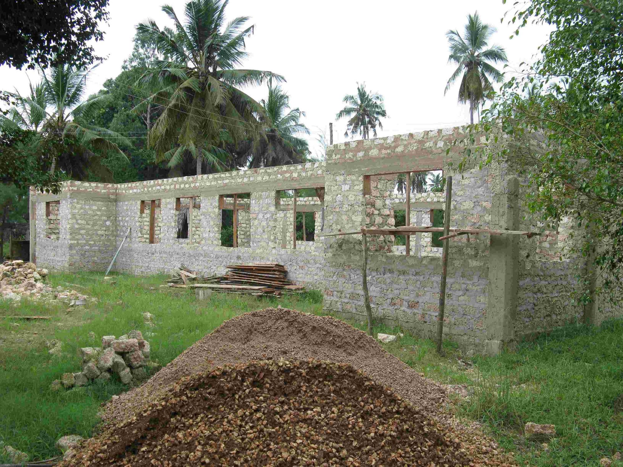 Unroofed block walls of the library building with a heap of gravel in front