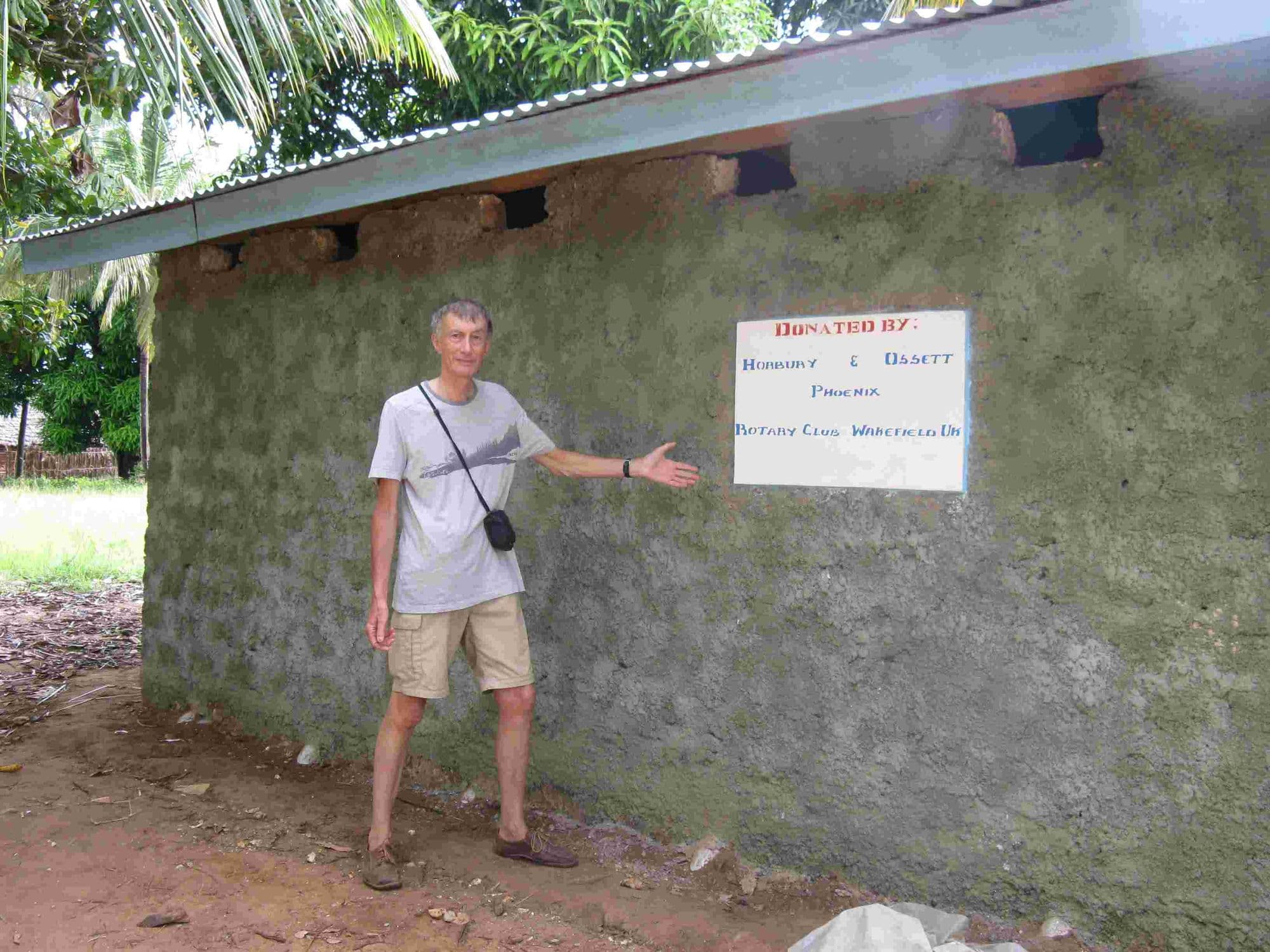 A visitor pointing to the donor sign on the wall of a new Rotary-funded toilet block