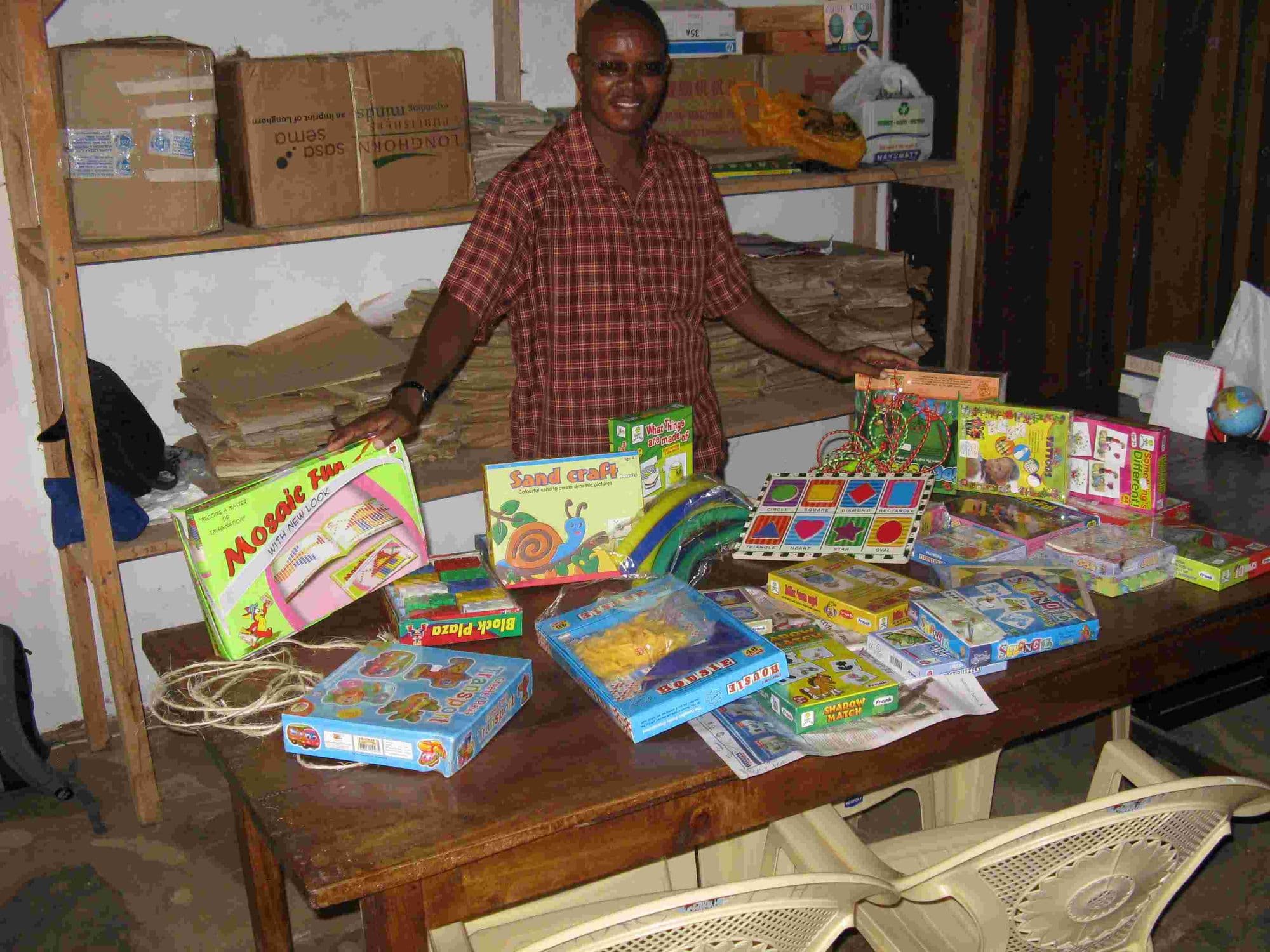 A man behind a table spread with donated toys, puzzles and games